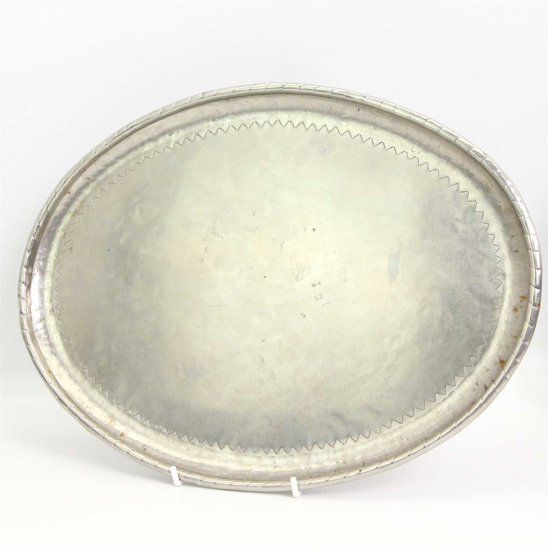 Large Arts & Crafts rectangular copper tray, with lightly hammered decoration and a shaped border, L70.5cm, Art Nouveau oval pewter two-handled tray by Hutton, Sheffield, L49cm over handles, and a stainless steel oval tray by Hugh Wallis, L36cm (3)