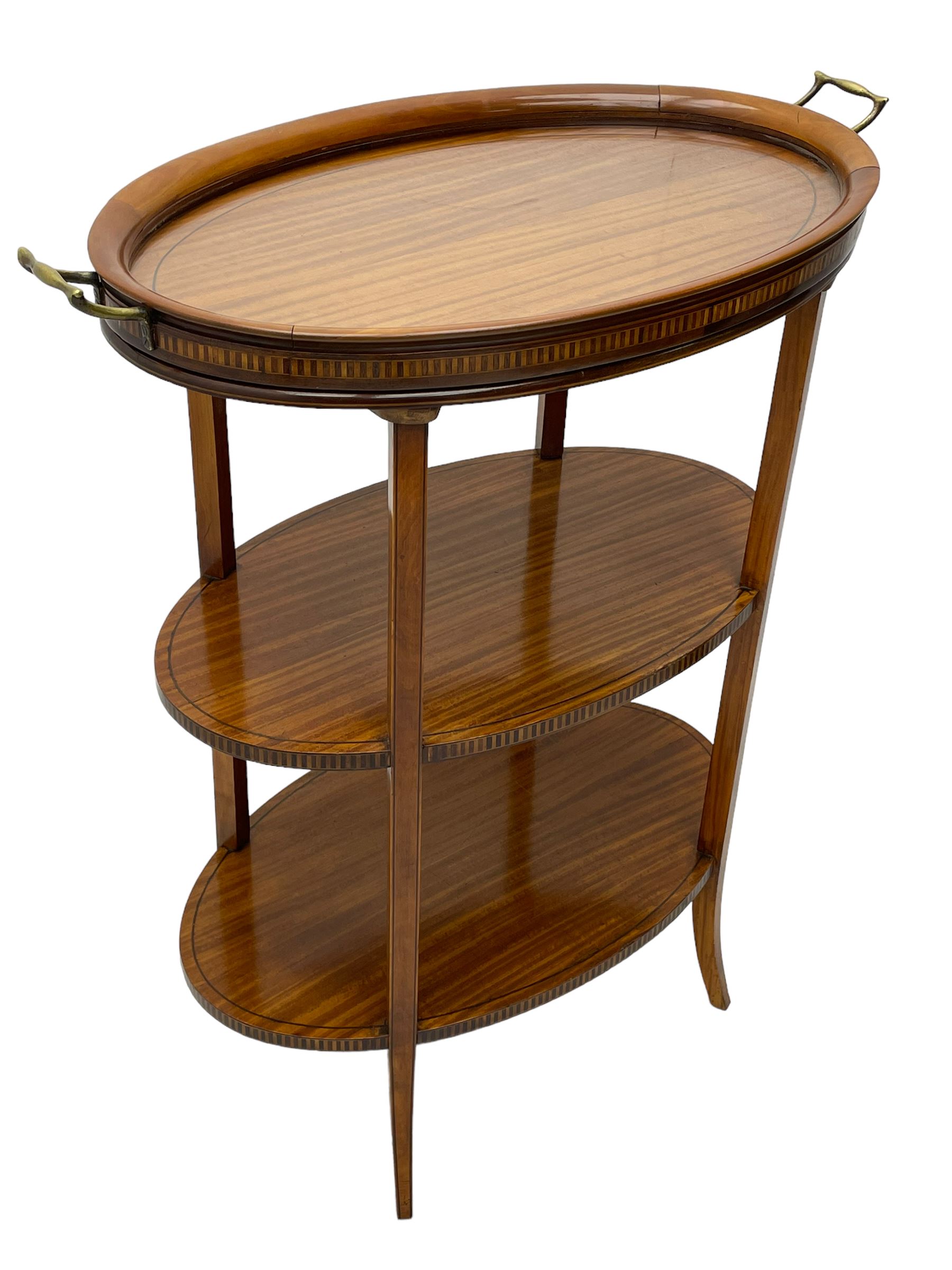 Edwardian satinwood tray top stand of oval form, tray top with glazed base and brass handles over two tiers, each with checkered inlaid band, on square tapering and splayed supports