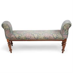 19th century mahogany framed bay window seat of tapered form, rolled arms decorated with carved scrolling, seat and arms upholstered in indigo ground floral patterned fabric, moulded lower rail over turned supports