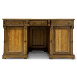 Late Victorian oak twin pedestal desk, chamfered rectangular top over three convex front edge drawers and two panelled cupboards, flanked by carved supports with roundels and diamond motif, on bracketed plinth base