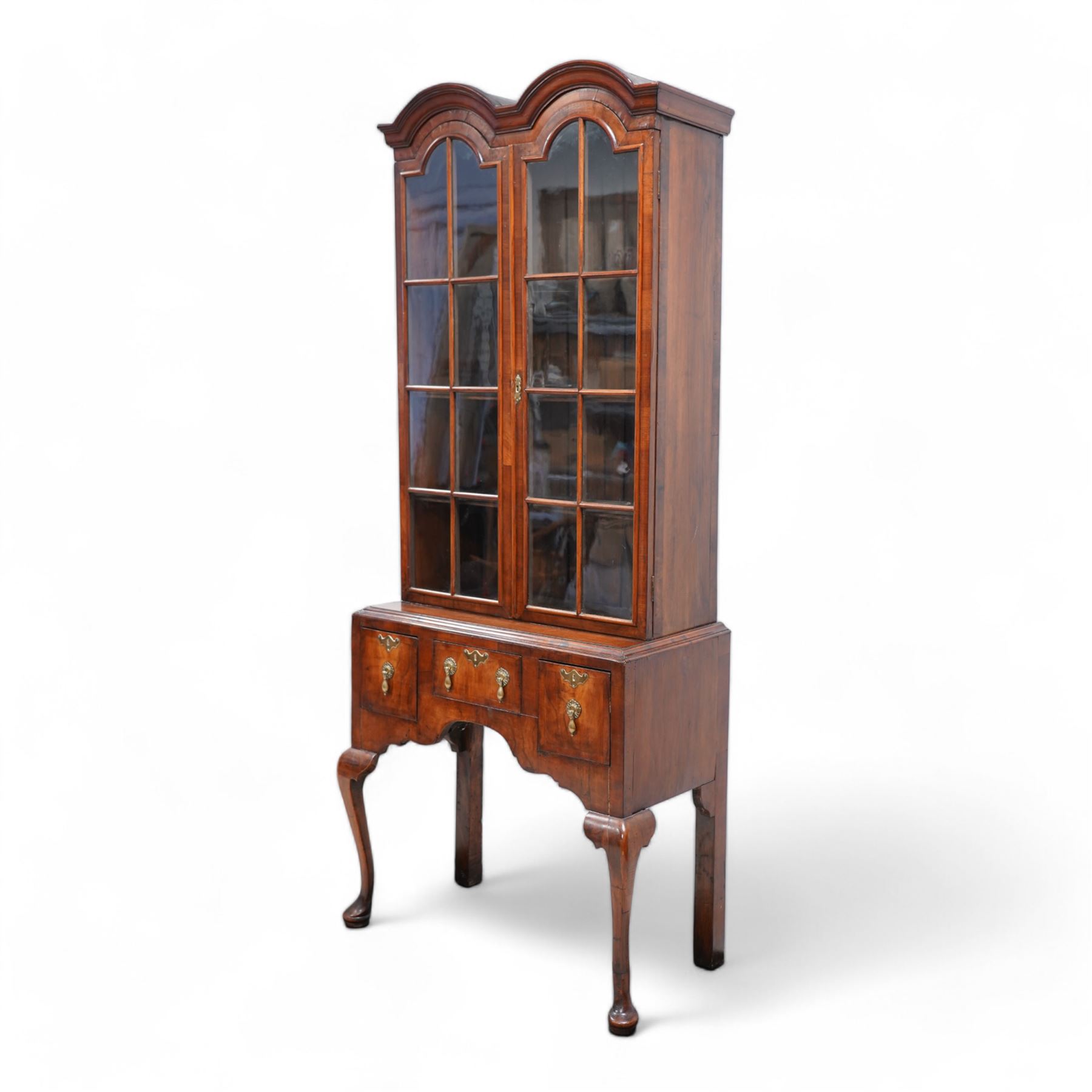 George II design walnut cabinet on stand, double arched top with applied mouldings over two astragal glazed doors, three internal shelves, the stand with moulded rectangular top fitted with three short drawers over shaped apron, on cabriole front supports 