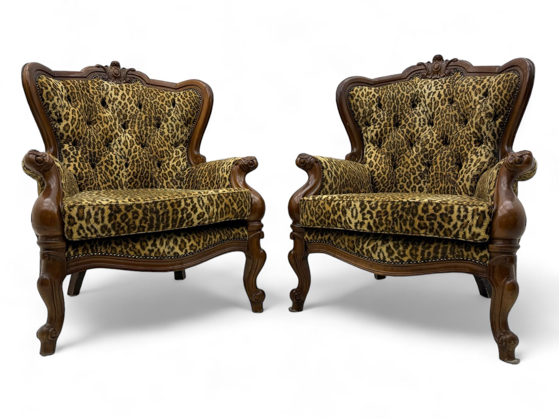 Pair of Victorian design stained beech armchairs, upholstered in leopard print fabric, with carved top rail over button-tufted backrest, scroll arms, serpentine front rail, raised on cariole supports