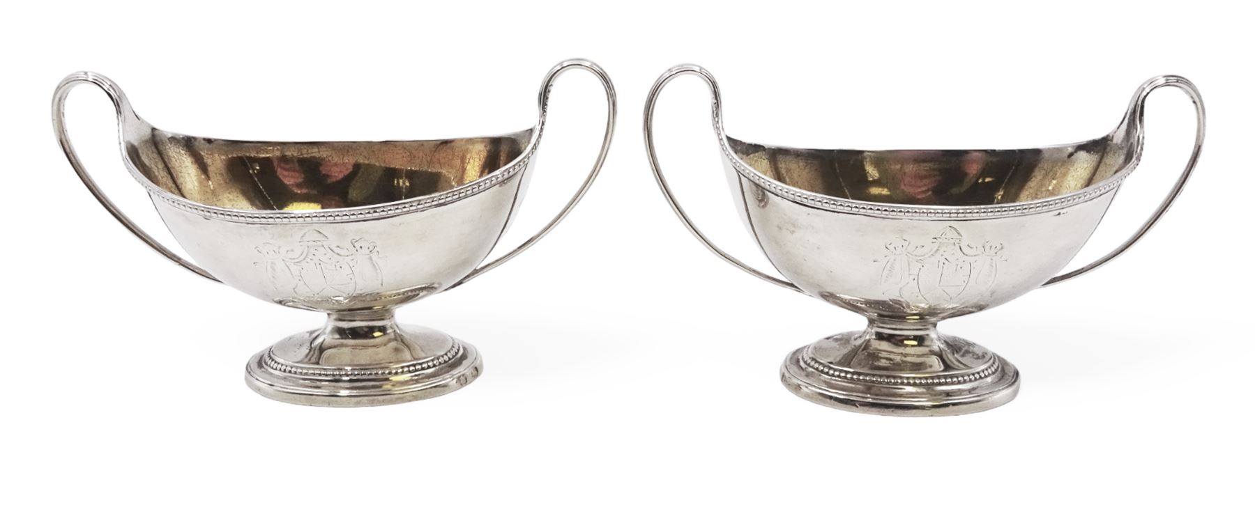 Pair of George III twin handled silver salts, of navette form with beaded rim and twin whiplash handles, each engraved to body with crest, upon stepped oval foot, London 1784, H8.5cm