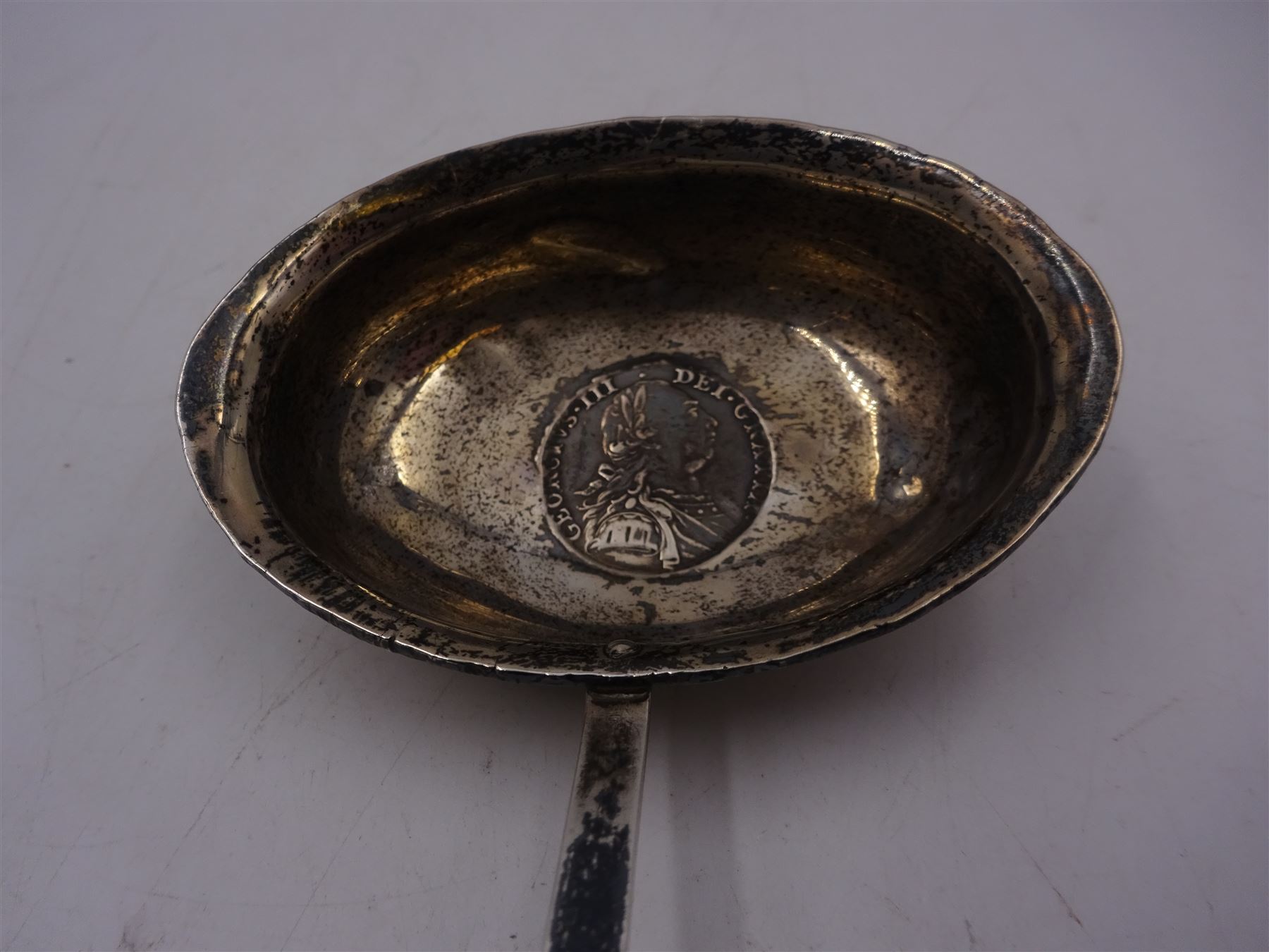 George III silver toddy ladle, the oval bowl set with a coin, with baleen twist handle, L40cm