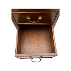 Late 20th century mahogany corner desk, leather inlaid top with gilt tooling, central frieze drawer flanked by two banks of four graduated drawers, raised on shaped bracket supports 