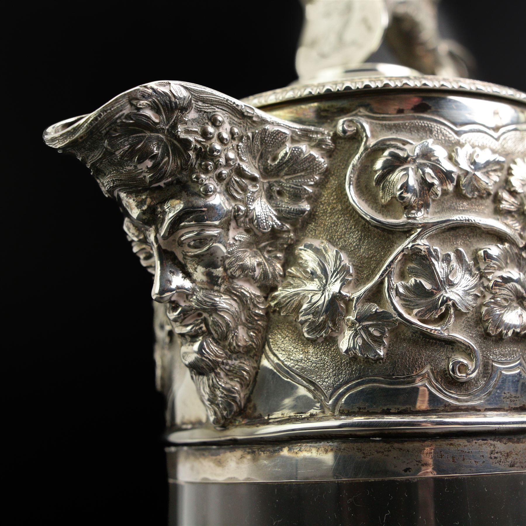 Victorian silver-mounted glass claret jug by George Richards Elkington, with Bacchanalian repoussé decoration and mask spout, with a domed hinged cover with a thumb-piece modelled as a rampant lion holding a shield, with engraved Dragon head crest, the glass body with etched greek key border and star-cut base, H29cm 