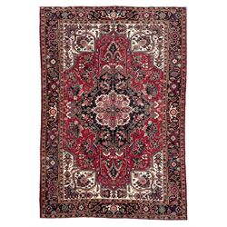 Persian Heriz red ground rug, central scrolled medallion on dark ground decorated with flo...