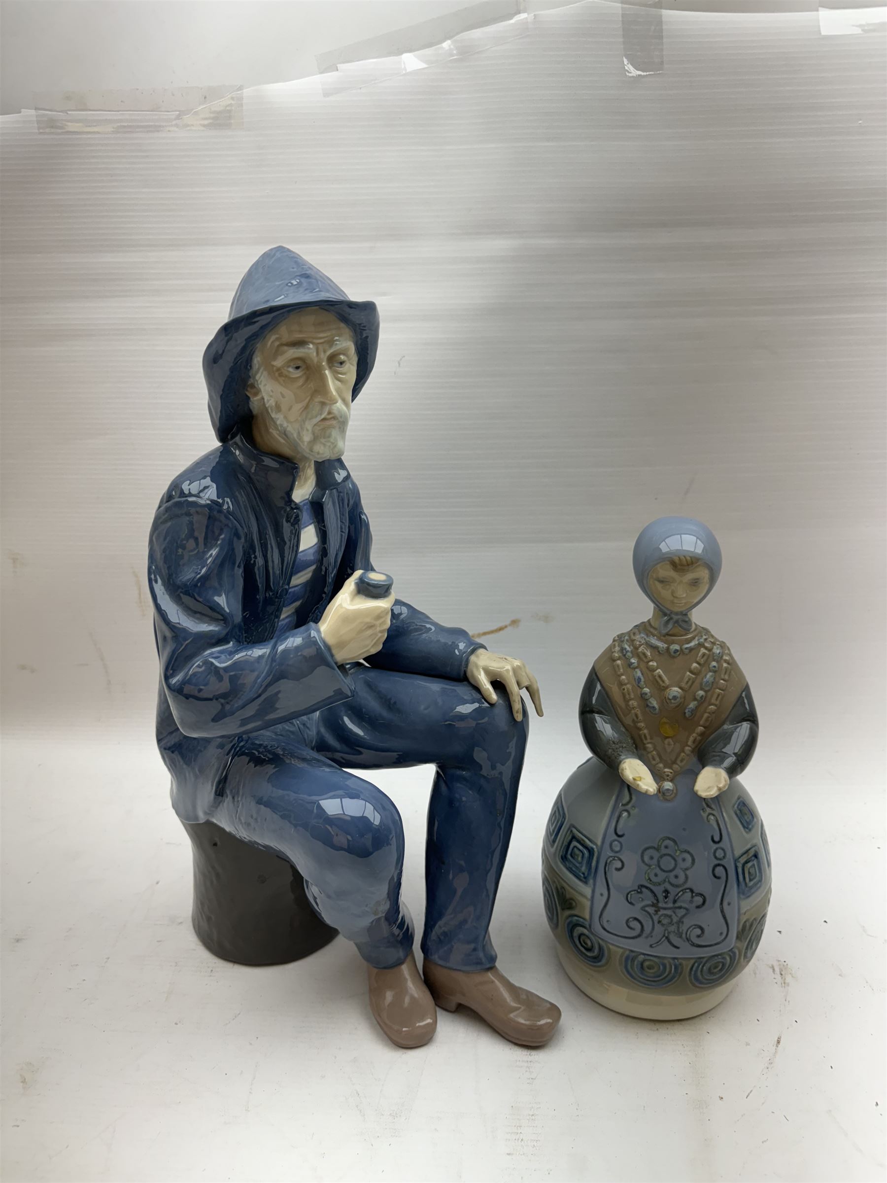 Lladro figure, Girl in Traditional Dress no 1159, together with Nao figure Old Fisherman Smoking a Pipe