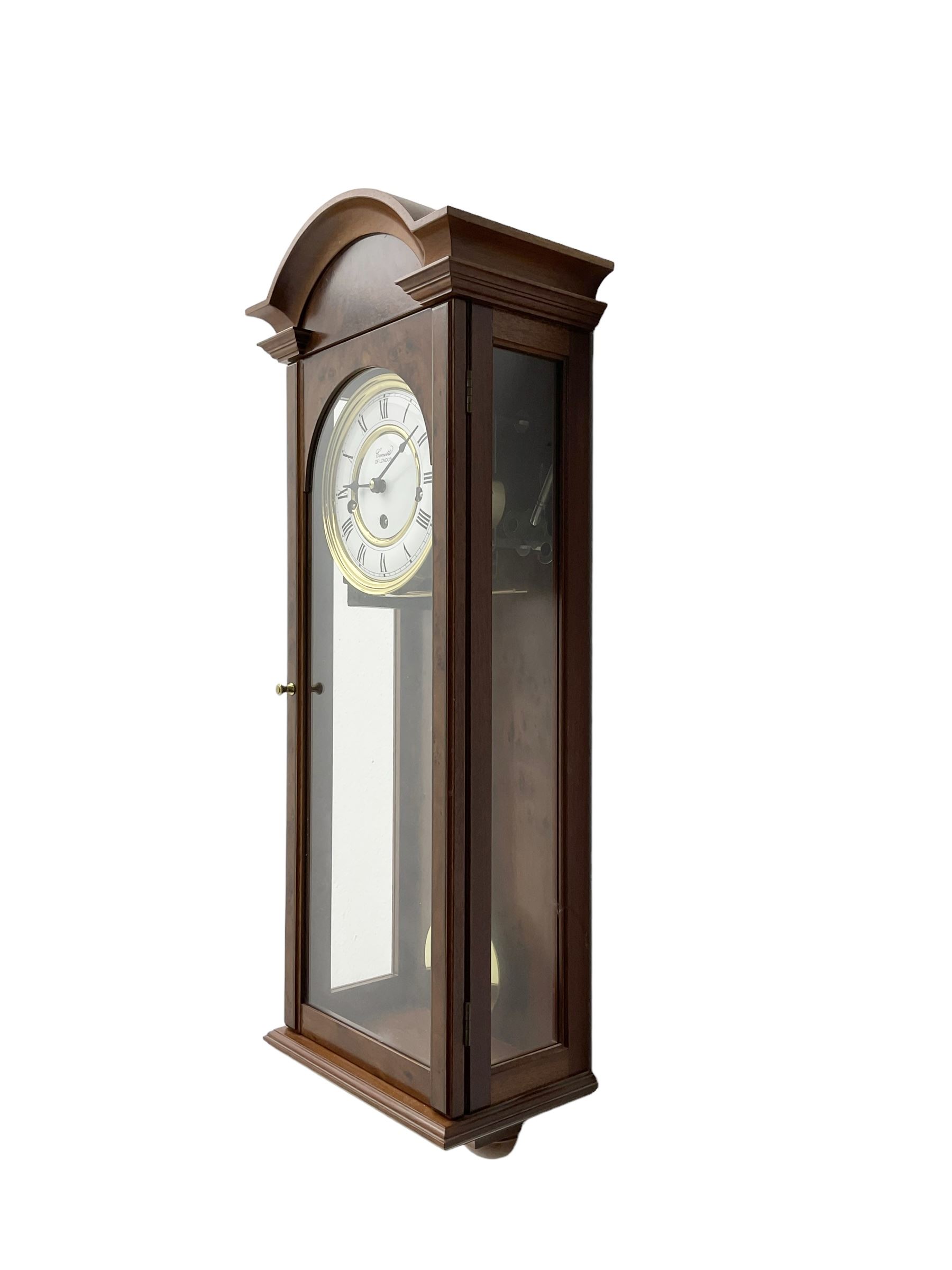 Comitti,  London - 20th century 8-day chiming wall clock in a walnut case, with a moulded break-arch top and full length glazed door and side panels, two part enamel dial with spade hands and visible gridiron pendulum, three train spring driven movement chiming the quarters on 5 gong rods.