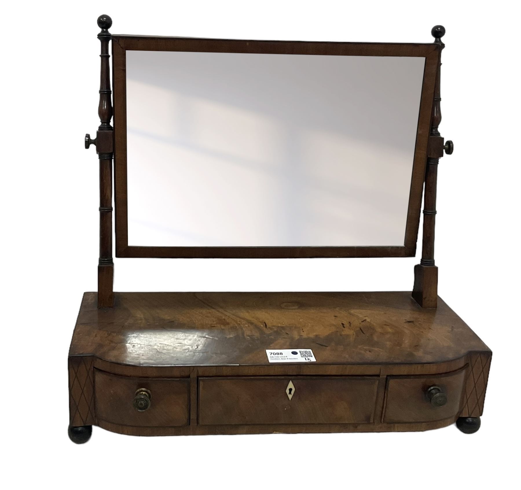 George III mahogany toilet mirror, rectangular plate on ring turned supports with swing action, three drawers with simulated ivory escutcheon, on ebonised bun feet