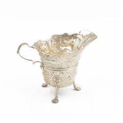 Edwardian Irish silver cream jug, of helmet form, profusely embossed with florals and anim...