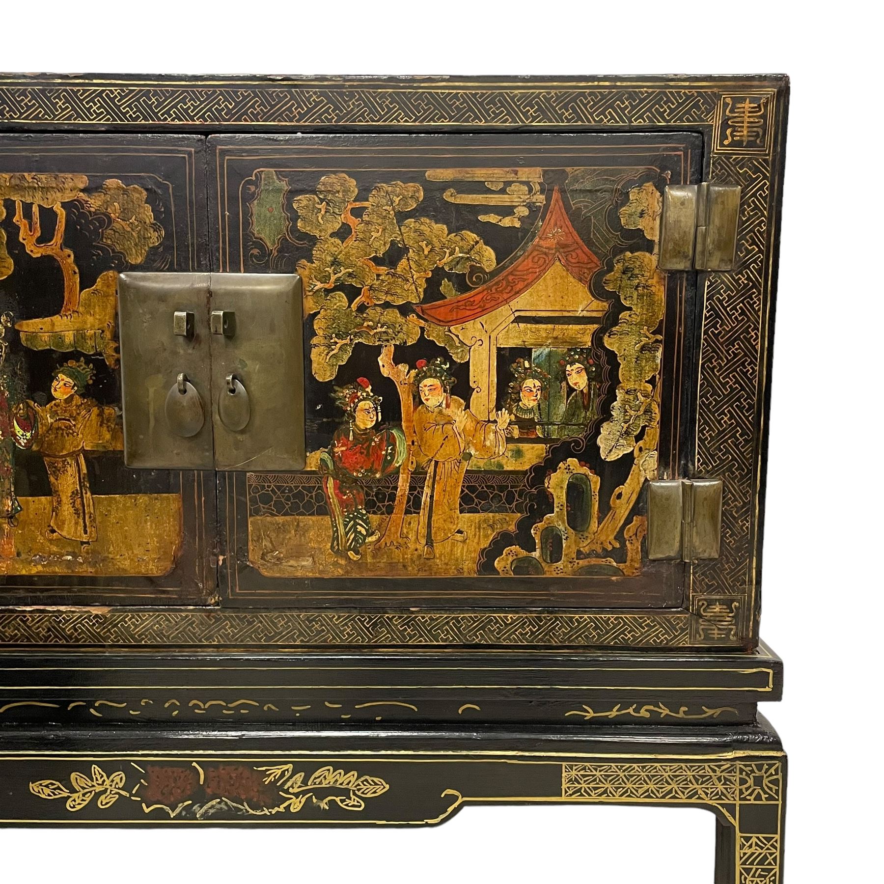 Pair of early 20th century Chinese ebonised and lacquered wood cabinets, the top decorated with dragons over lapping waves within a gilt patterned panel, the surrounding band decorated with Chinese symbols and flowerheads, enclosed by two doors each with village scenes with pagodas, figures and trees, the panelled sides decorated with a figure riding a dragon on stands with gilt decorated 