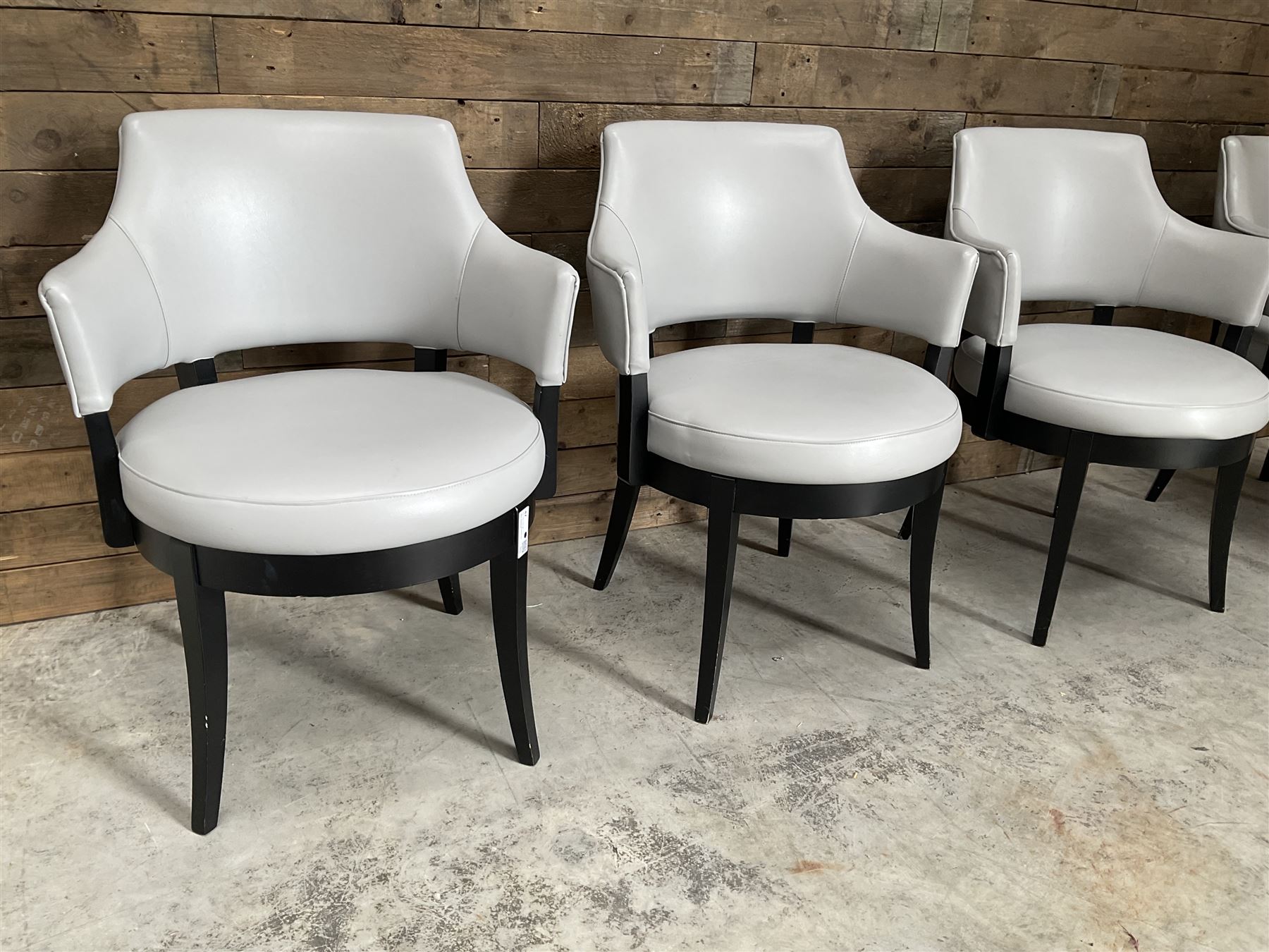 Four ebonised framed tub shaped armchairs, upholstered in grey fabric