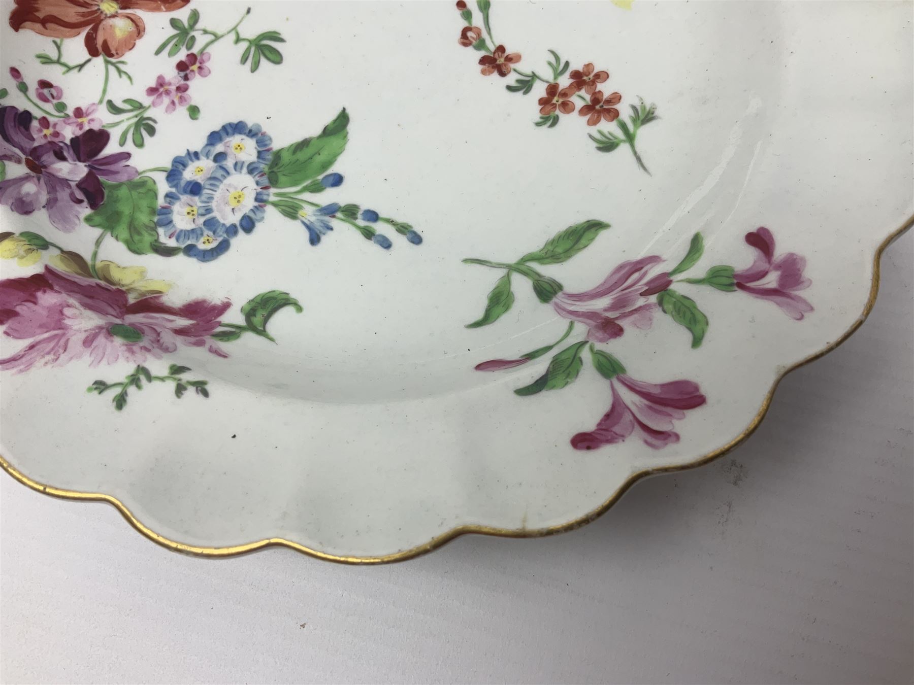 Three 18th century Worcester desert dishes, the first example decorated in the Scarlet Japan pattern, circa 1790, painted with alternating panels of Kakiemon style prunus blossom and chrysanthemum, and orange ground panels with gilt fret detail, D19cm, the second example, circa 1770, decorated with Kakiemon style chrysanthemums and foliage within shaped reserves upon a blue scale ground, with fretted square pseudo mark beneath, D19cm, and the third, circa 1770, painted with polychrome floral sprays and sprigs, D20cm