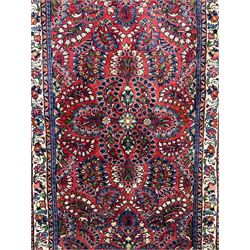 Small Persian red ground rug, the field decorated with an overall floral design, guarded ivory ground border decorated with trailing flower heads and foliage