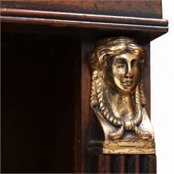 Pair of Neoclassical Empire design mahogany open bookcases, the rectangular top with reeded edge over a plain frieze decorated with a brass mount of the Greek god Hermes, the single shelf flanked by reeded square pilaster uprights, surmounted by a brass capital in the form of a female Egyptian bust, with human feet terminals, lower moulded edge on skirted base