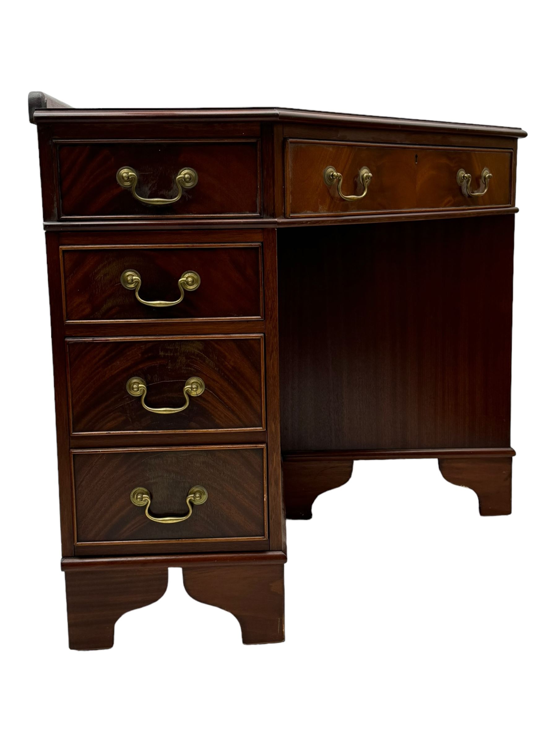 Late 20th century mahogany corner desk, leather inlaid top with gilt tooling, central frieze drawer flanked by two banks of four graduated drawers, raised on shaped bracket supports 