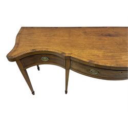 Large George III mahogany serpentine serving table, shaped top with crossing banding and stringing, the frieze fitted with three cock-beaded drawers, oval pressed brass handle plates decorated with urns, on square tapering supports with spade feet 