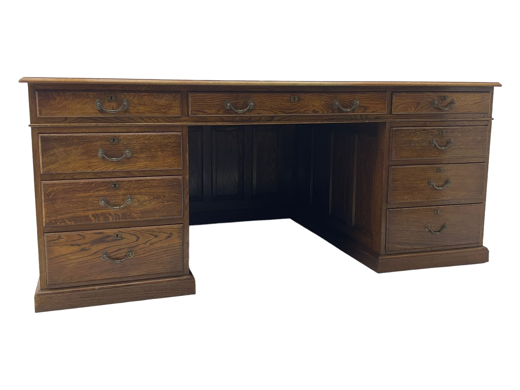 Large 20th century oak twin pedestal desk, moulded rectangular top over nine drawers, panelled pedestals, on moulded plinth base 