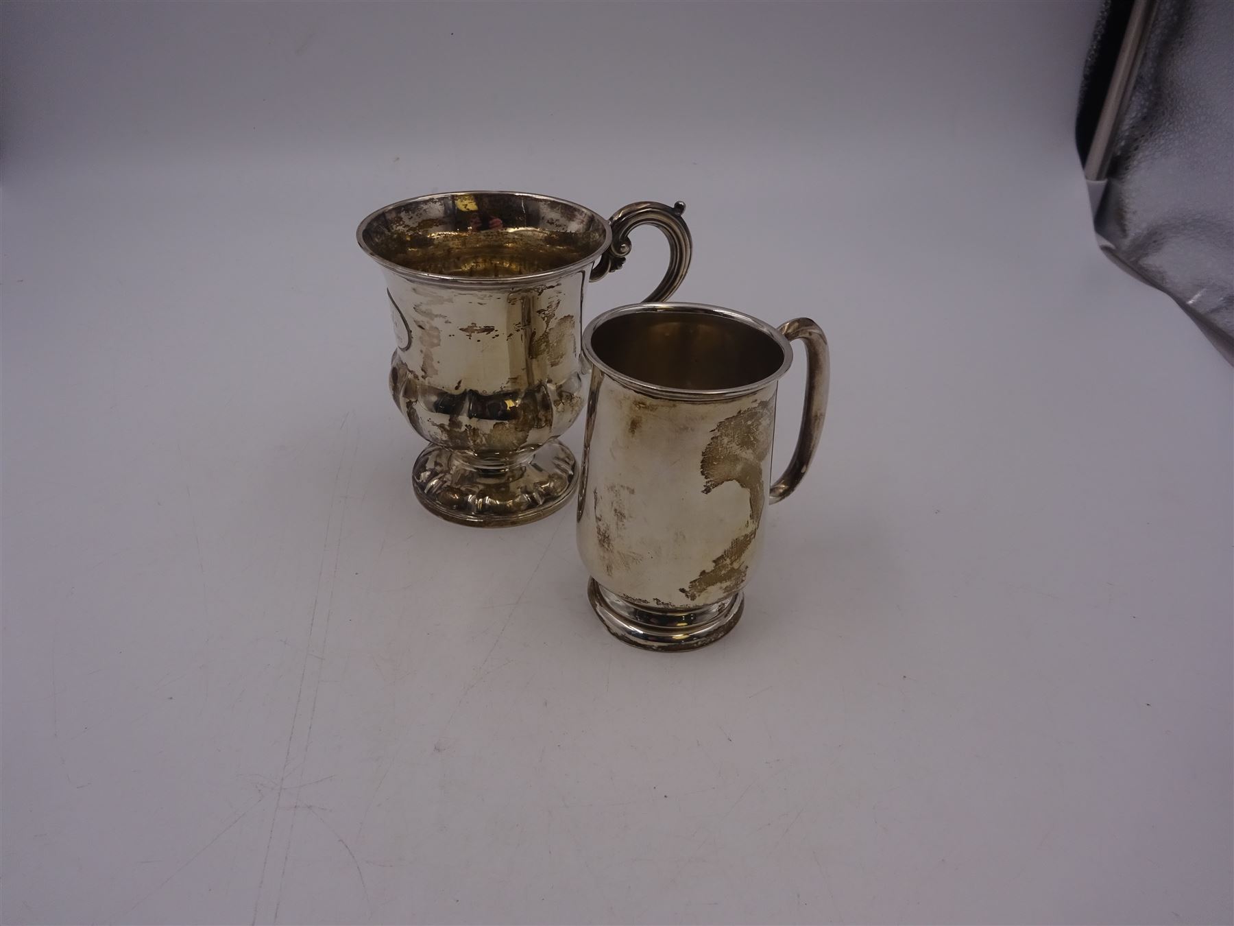 Two silver christening mugs, the first a Victorian example, of part fluted waisted form, upon circular foot with scroll handle, hallmarked Edward, John & William Barnard, London 1838, the second example of plain slightly tapering form with C handle, hallmarked S Blanckensee & Son Ltd, Chester 1929, tallest H9cm