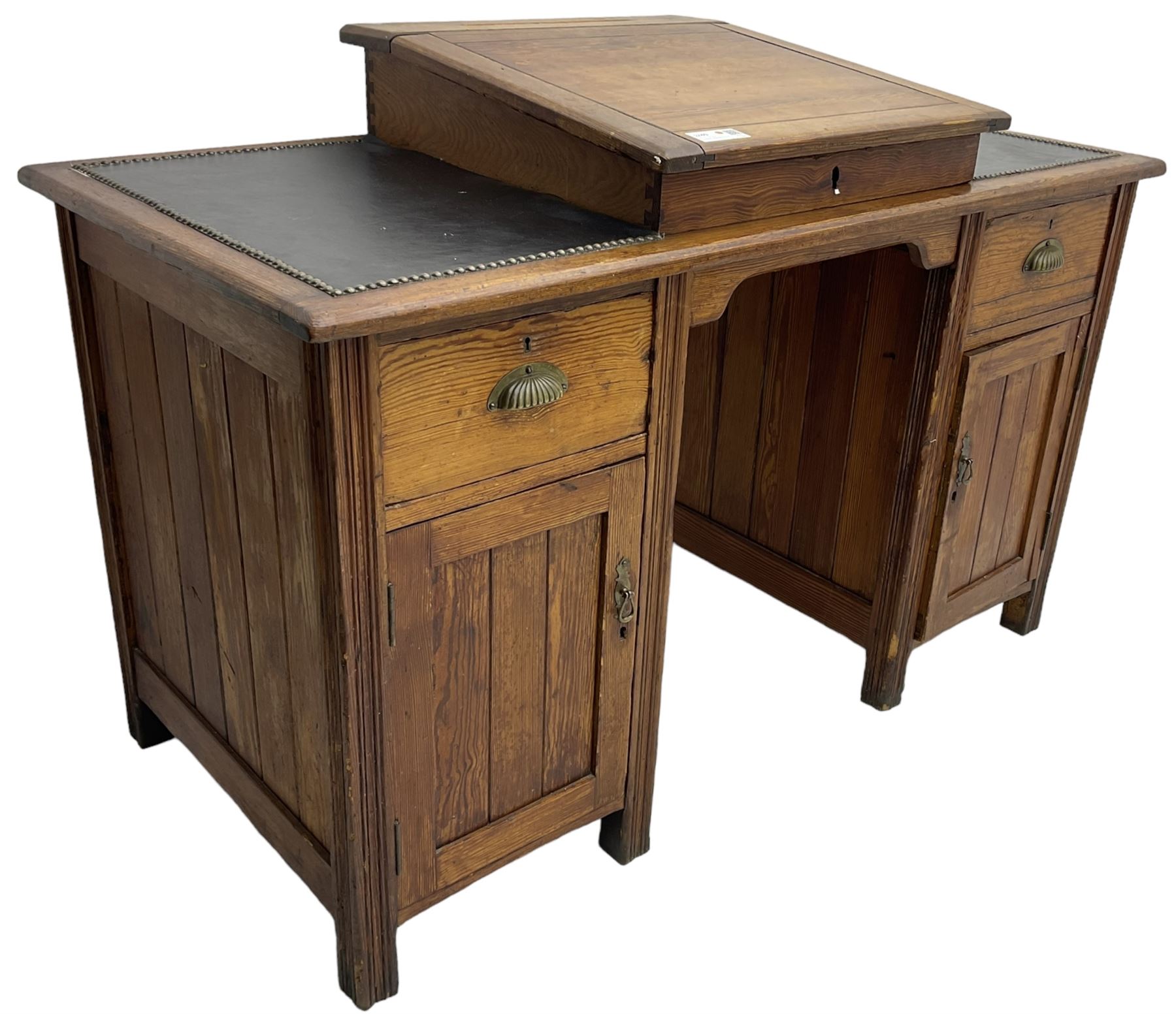 Edwardian pitch pine desk, rectangular top with writing slope flanked by inset leather writing surfaces, over twin pedestals each with shell cup handled drawer over cupboard, the left enclosing two shelves, the right enclosing sliding trays, on fluted straight supports