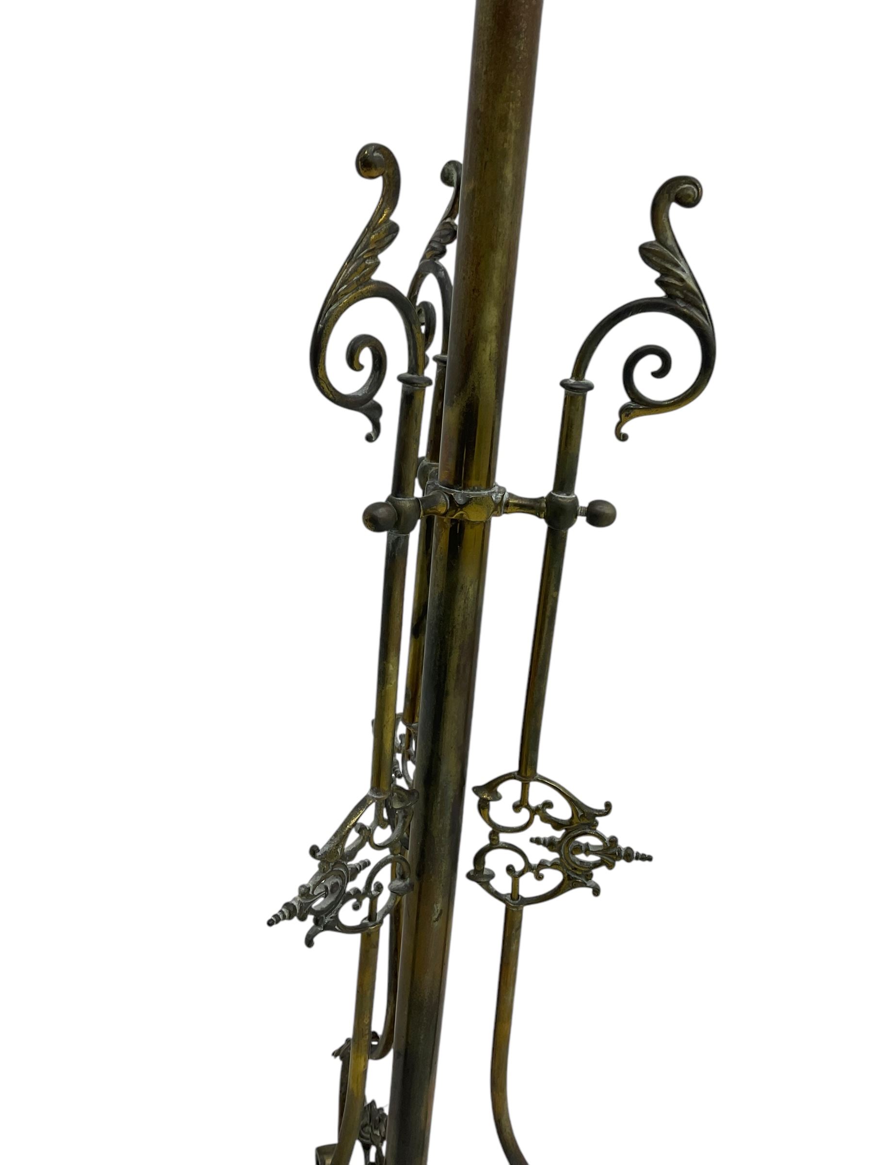 Victorian brass converted oil lamp stand, telescopic stem with scrolled uprights terminating to scrolled feet, dished base decorated with scrolling cast metal work and grotesque masks 