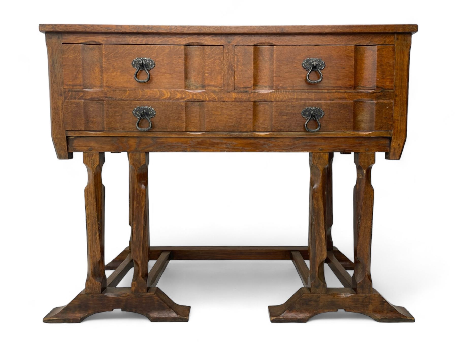 Arts & Crafts design oak chest on stand, rectangular top over two short and one long drawer, on a series of shaped and tapered supports with carved and beaded decoration, united by chamfered stretchers rails, on sledge feet 