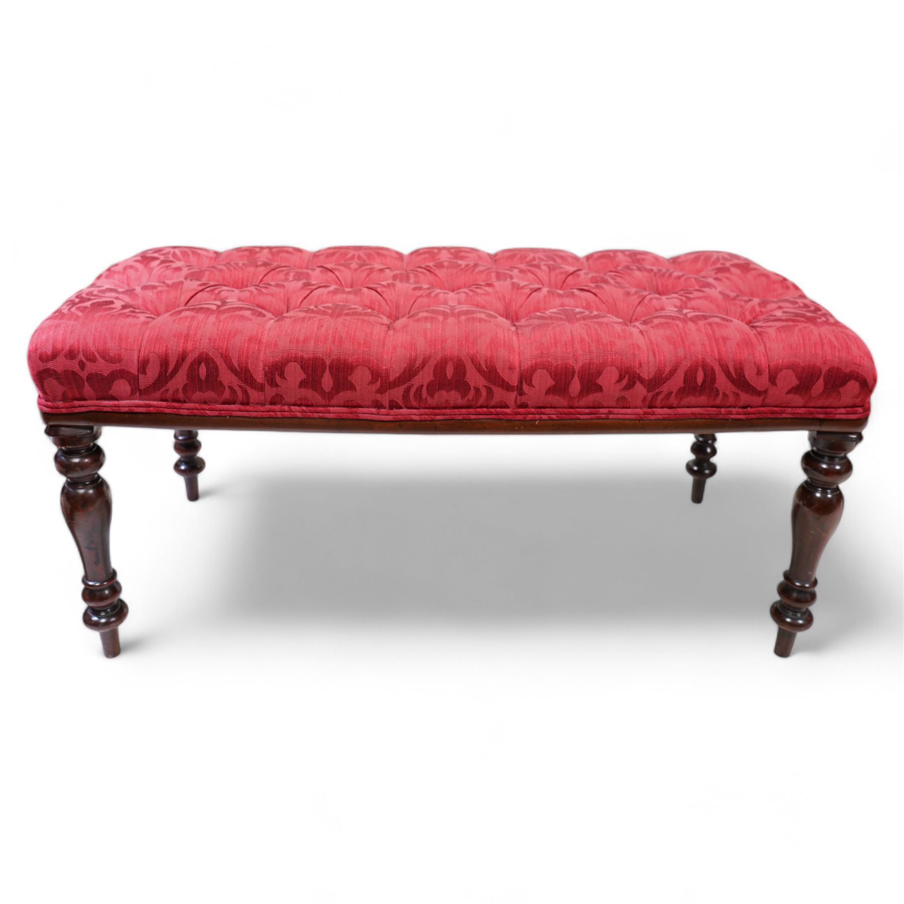 Victorian design mahogany footstool, rectangular form, the seat upholstered in red buttoned fabric with stylised foliate pattern, on turned supports 