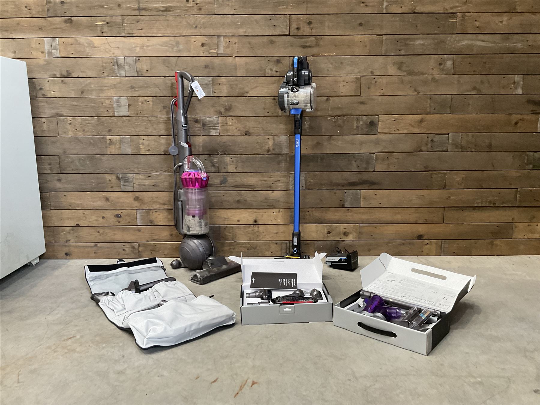 Dyson DC40 vacuum cleaner with various attachments, and a Vax cordless vacuum cleaner with single battery and charger