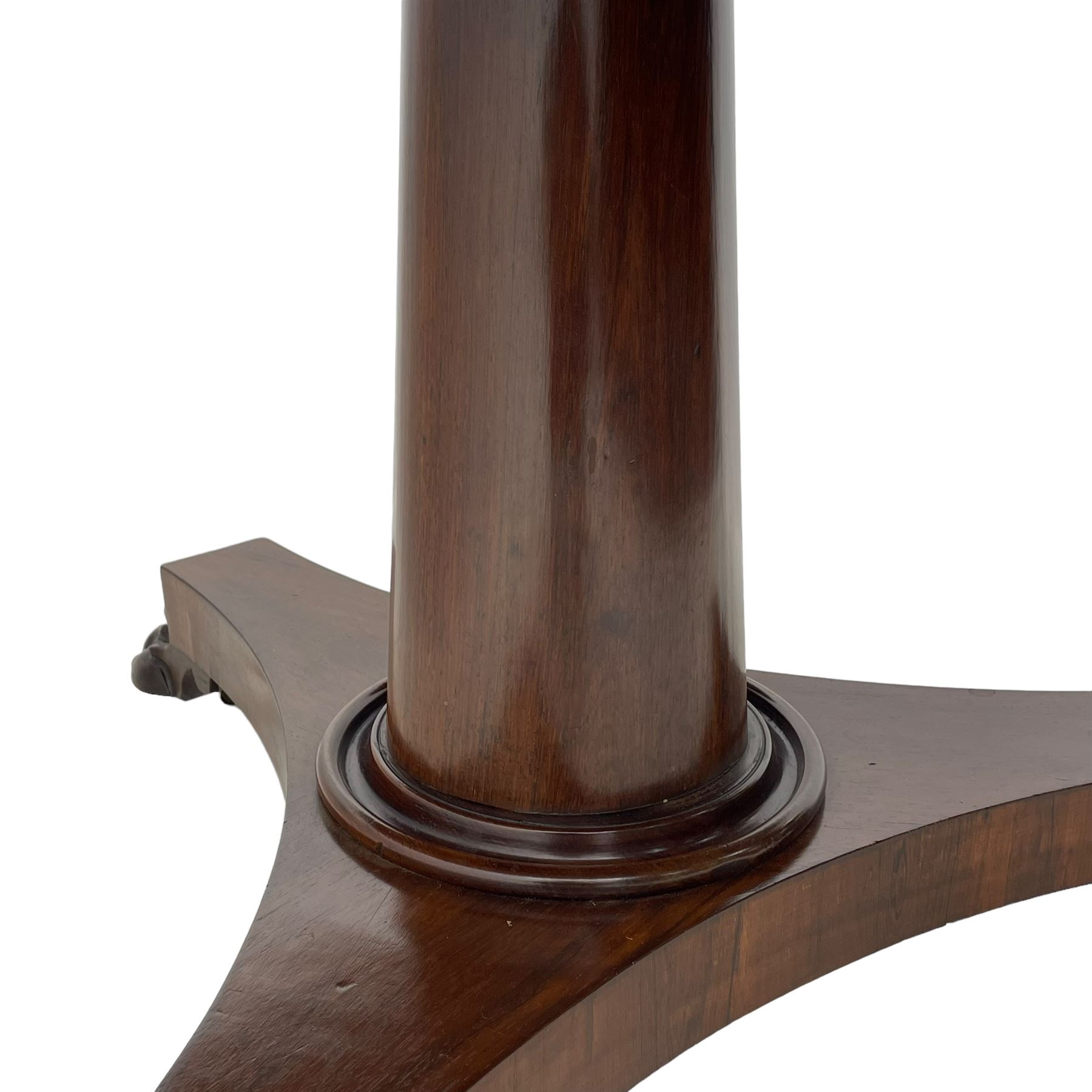 Mid-19th century rosewood breakfast or centre table, circular tilt-top on tapered barrel pedestal, concaved triangular platform, on carved paw feet with castors 