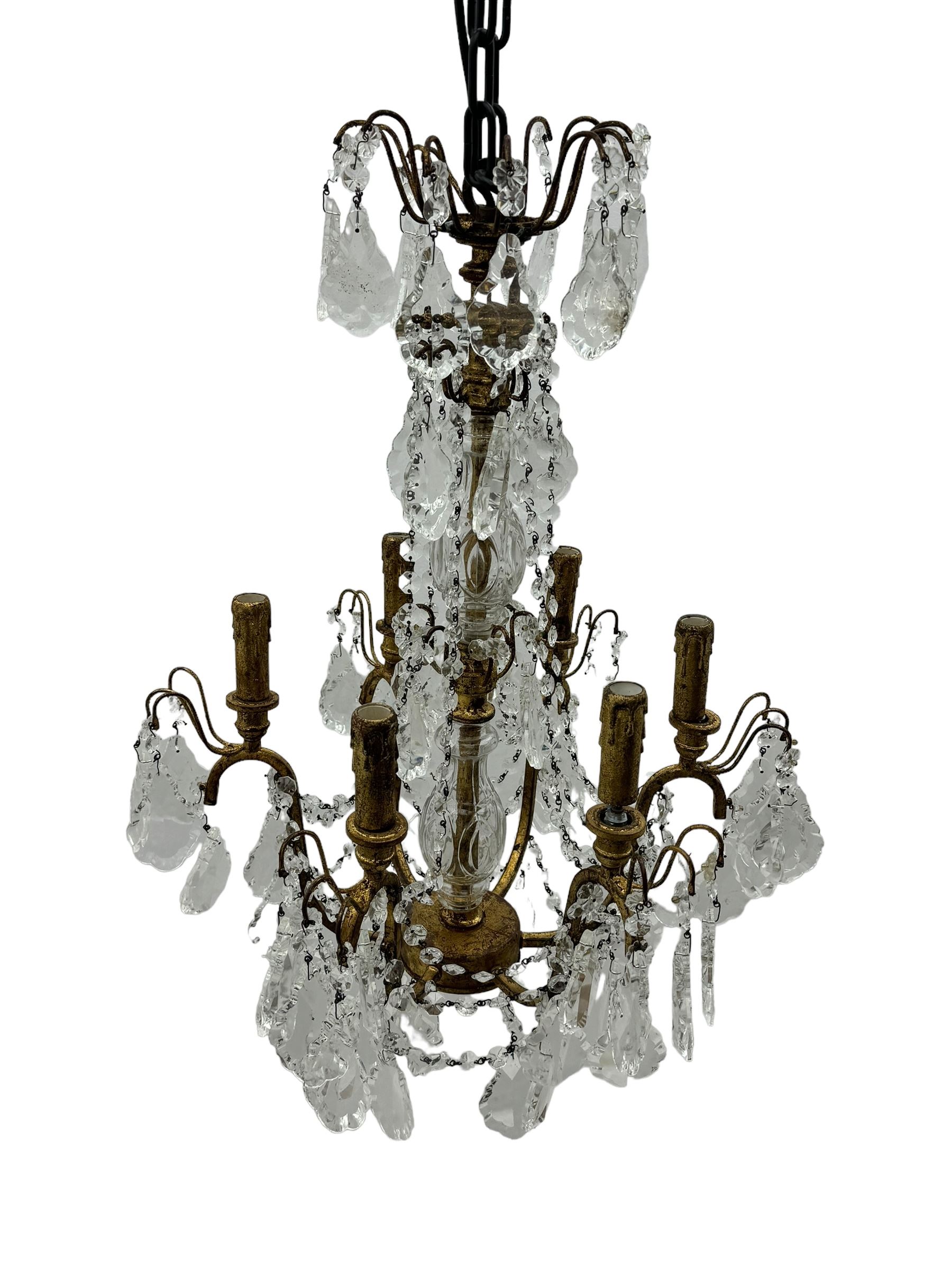 India Jane Interiors - brass and crystal six-branch chandelier, each branch holds a single candle-style bulb holder detailed with scrolling design, the chandelier is adorned with numerous crystal pendants and octagonal beads, which hang from each arm and from the cut crystal central column