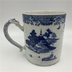 Two large 18th century Chinese blue and white tankards, each of cylindrical form, the first example with foliate mounted strap handle, the body painted with a shaped panel depicting a riverside landscape with pagodas and pine trees, against a textured ground decorated with floral sprays, H15cm D12cm, the second with serpent handle, the body painted with a similar riverside landscape, H14cm D12cm