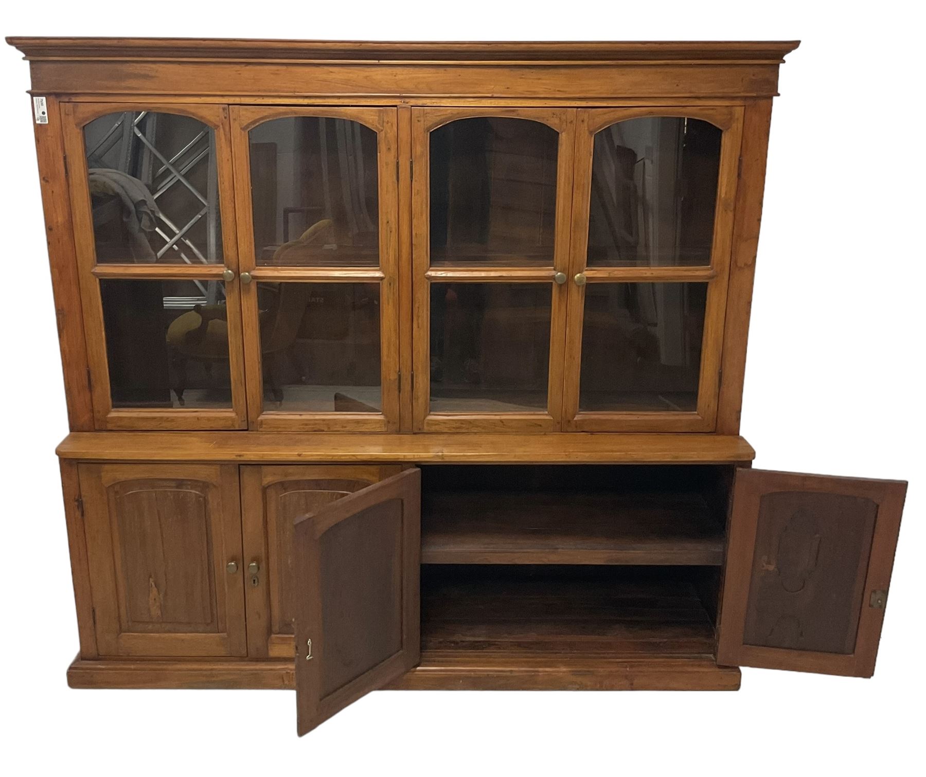 Mid-to-late 20th century Burmese teak wall cabinet, four glazed doors over four panelled doors, on moulded plinth base 