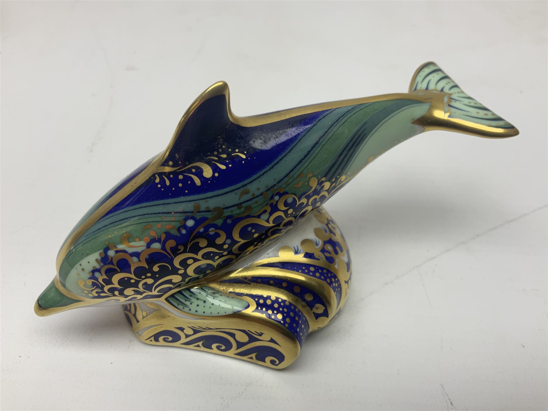 Three Royal Crown Derby paperweights, comprising Bottlenose Dolphin, Baby Bottlenose Dolphin and Striped Dolphin, all with gold stoppers 