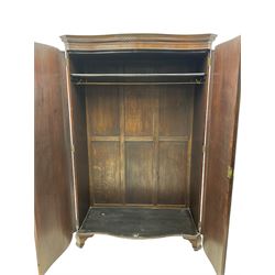 Early 20th century mahogany serpentine double wardrobe, moulded cornice over two figured doors, the interior fitted with hanging rail and shelf, canted and fluted uprights, on bracket feet 