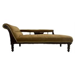 Late 19th century mahogany framed chaise longue, upholstered in tan fabric, featuring scrolled backrest with carved floral motifs, supported by turned legs