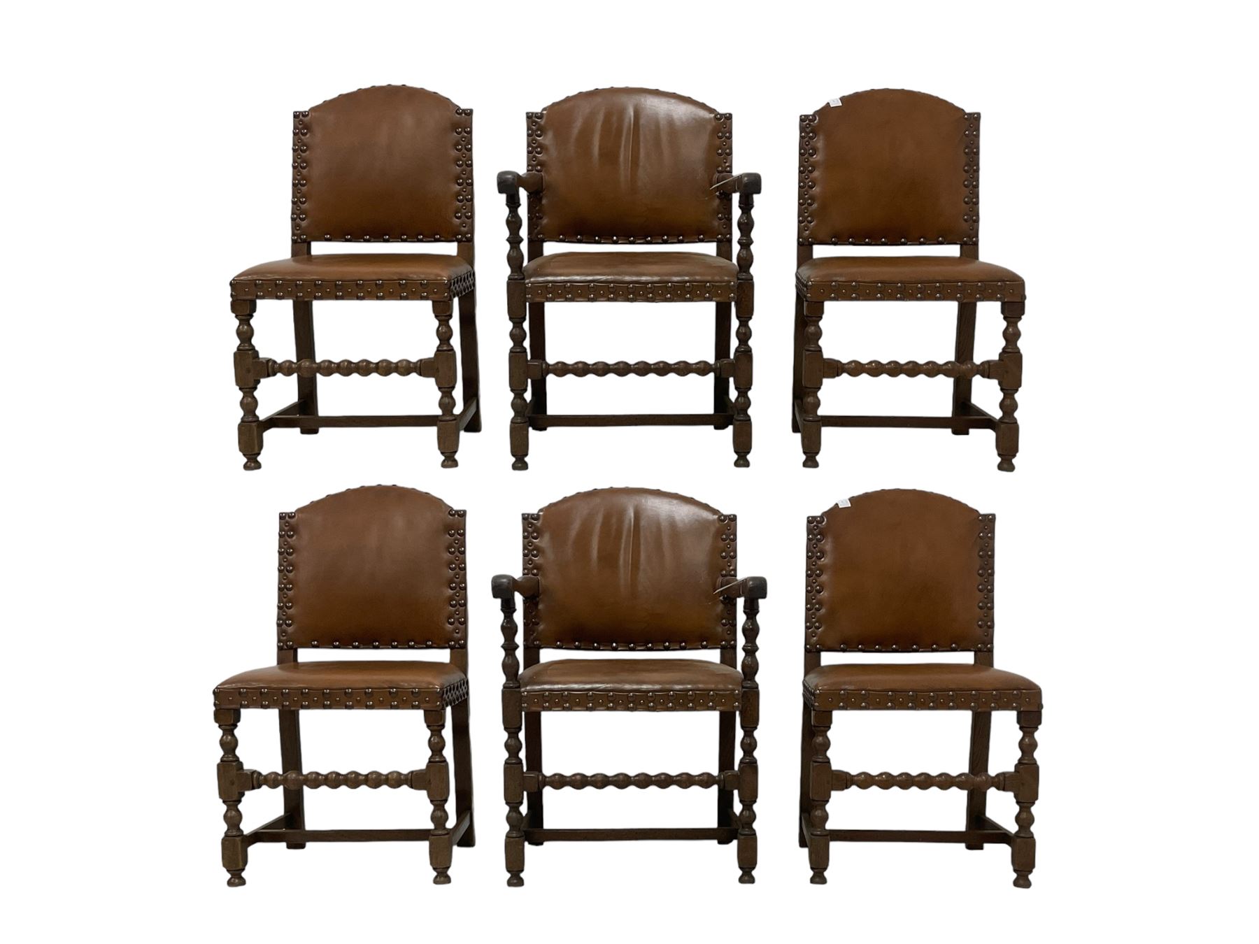 Set of six (4+2) early 20th century oak dining chairs, arched back and seat upholstered in tan leather with studwork detail, on turned supports united by bobbin-turned stretchers