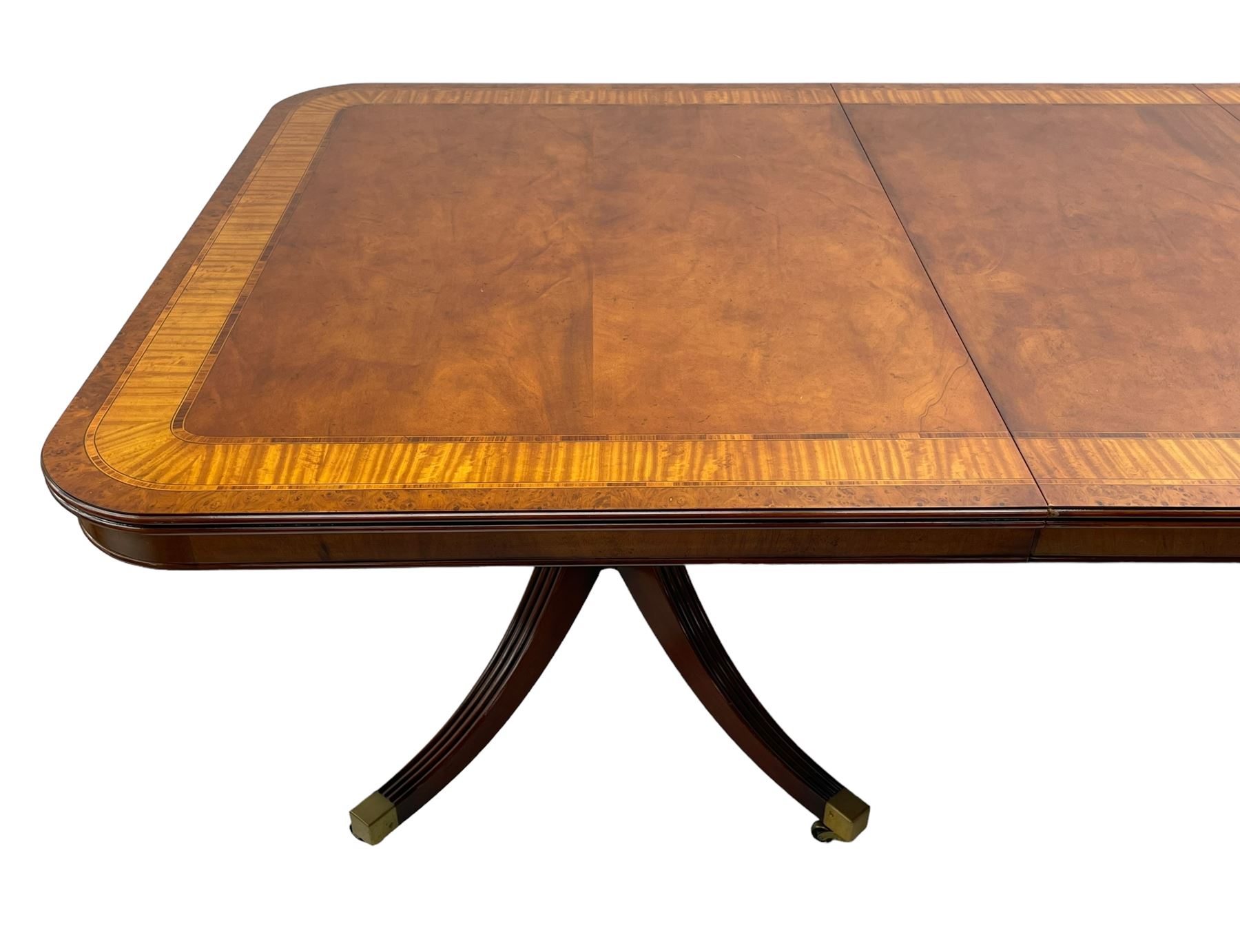 RBC Furniture (Made in England) - Georgian design mahogany dining table, rectangular top with rounded corners, satinwood and burr walnut bandings, two D-ends with two additional leaves and support rails, on barrel turned pedestals with four out-splayed reeded supports, brass cups and castors 