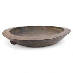 Large African hardwood bowl, of circular shallow form, the rim with chip-carved zigzag decoration, the underneath carved with handles; together with ladle, with similar chip carved decoration D51cm 