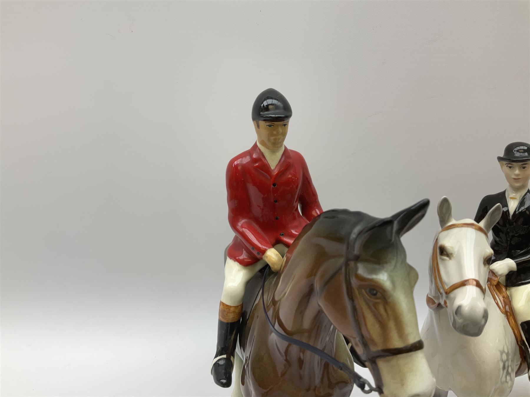 Beswick Hunting Group, comprising: two huntswoman on grey horses, model no 1730, huntsman on a bay horse, model no 1501, a seated fox, model no 1748, eighteen fox hounds and a spaniel, model no 967, all with printed marks beneath, together with three other ceramic huntsman on horseback and two hounds. 