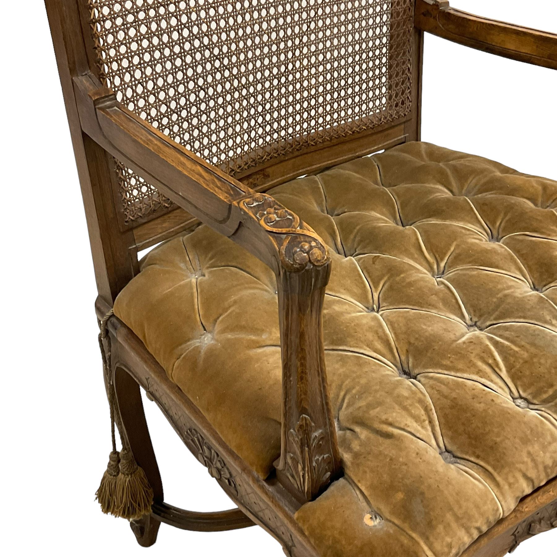 Late 19th century French carved beech open elbow chair, shaped cresting rail carved with central shell and curl leafage, cane work seat and back with buttoned loose seat cushion, the open arms carved with scrolled terminals and acanthus leaves, on cabriole supports with carved decorated united by shaped and moulded x-framed stretchers 