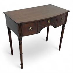 George III mahogany kneehole dressing or writing table, stepped bow-front form, reed moulded top with mahogany crossband, fitted with three cock-beaded drawers with circular pressed brass handle plates decorated with urn and beaded ring handle, on ring turned supports 