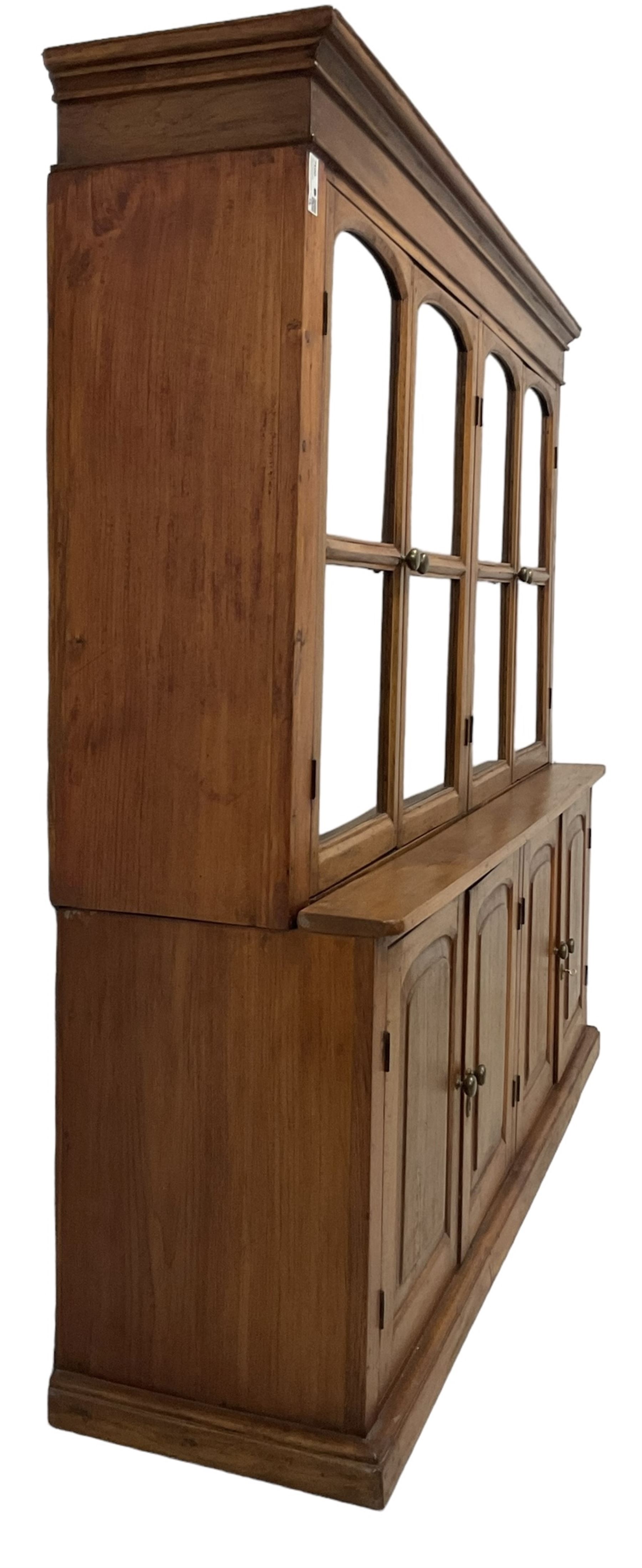 Mid-to-late 20th century Burmese teak wall cabinet, four glazed doors over four panelled doors, on moulded plinth base 