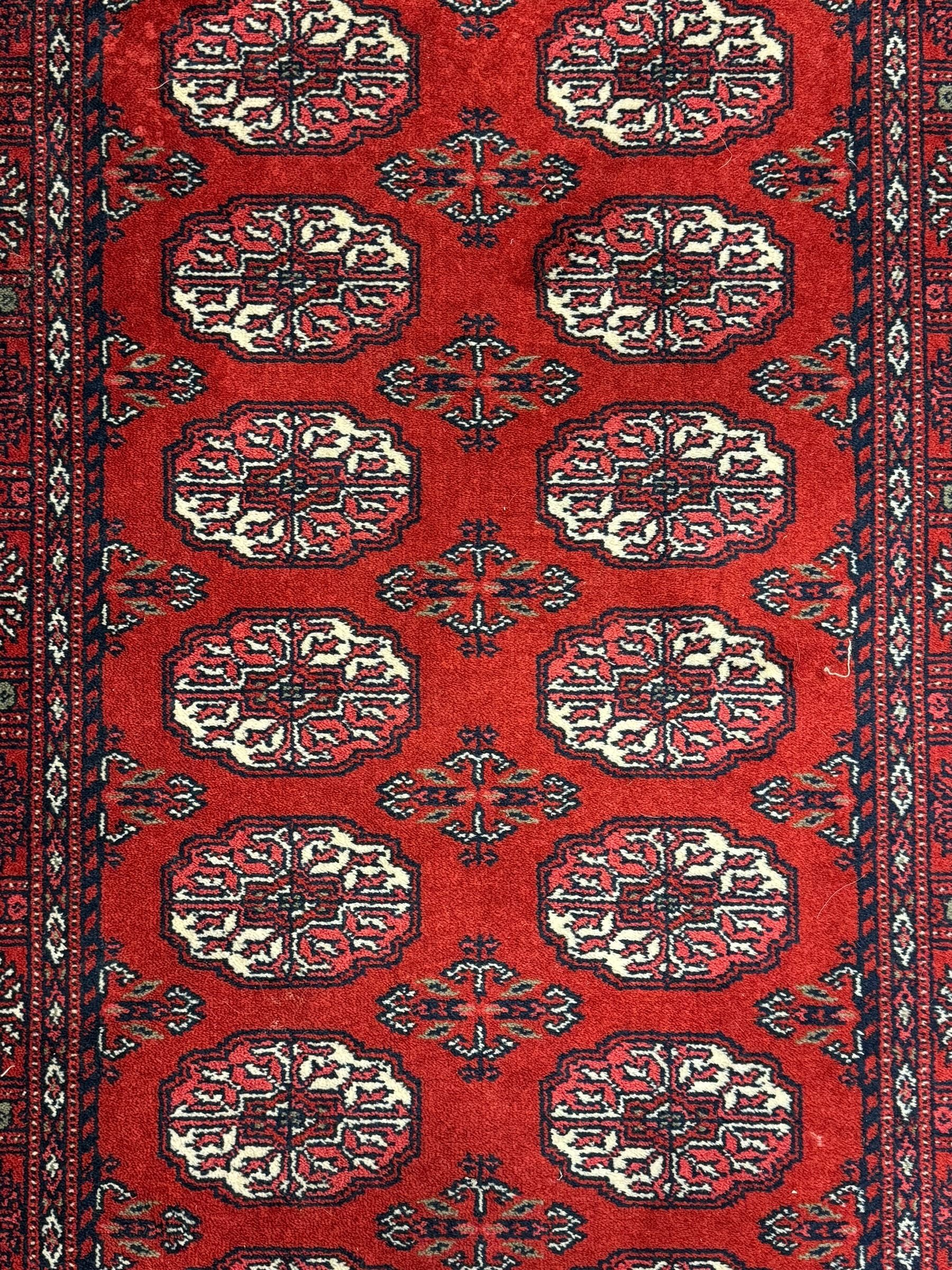 Persian Bokhara crimson ground runner rug, the field with a series of repeating ivory octagonal medallions, main border with repeating flower head pattern and diamonds within multiple guard stripes