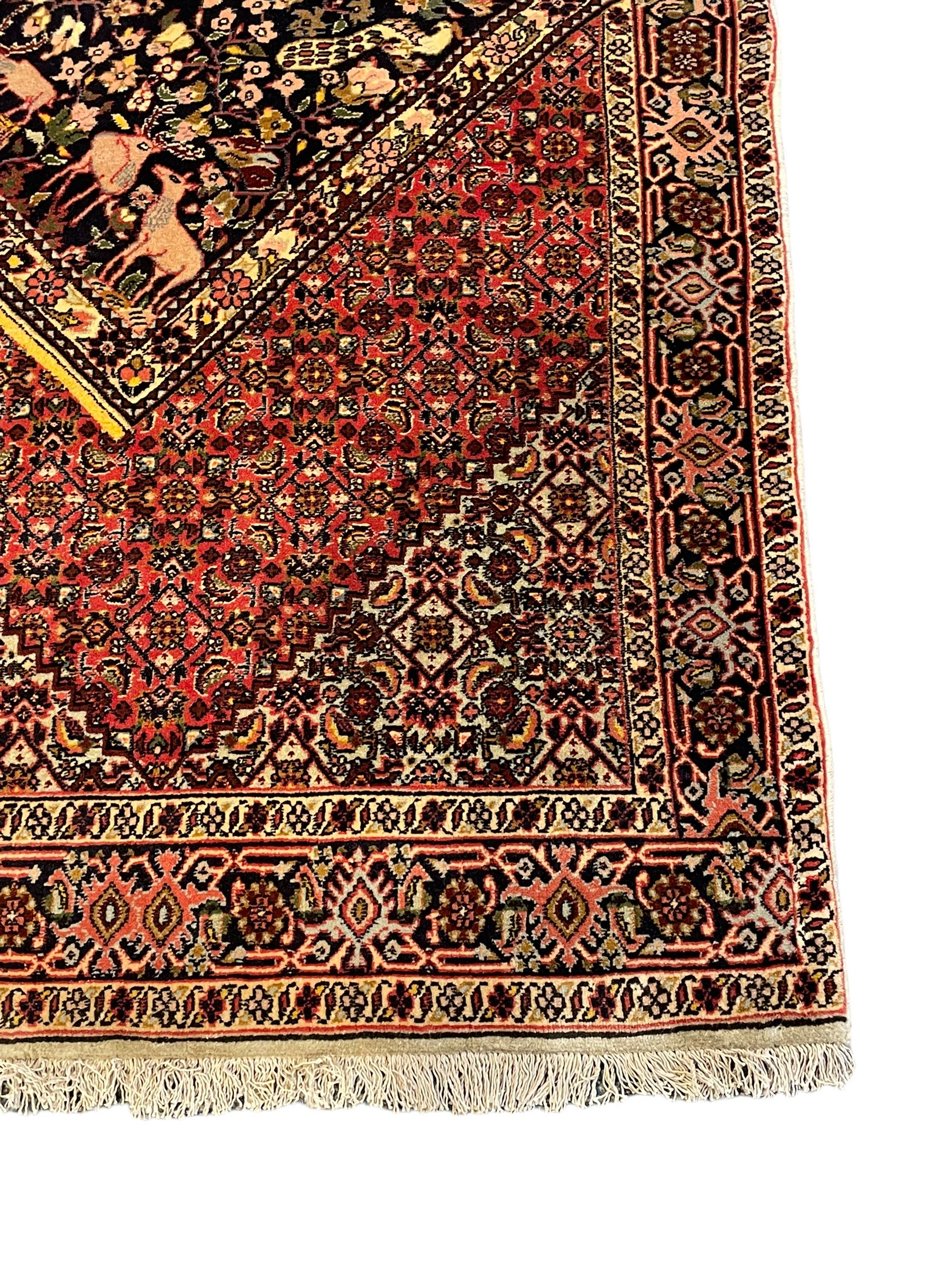 Persian Bidjar peach ground rug, the field decorated with repeating Herati motifs surrounding an off-centre lozenge medallion, decorated with grazing deer and peacock motids, the field border decorated with repeating stylised plant motifs, multiple floral design guard bands