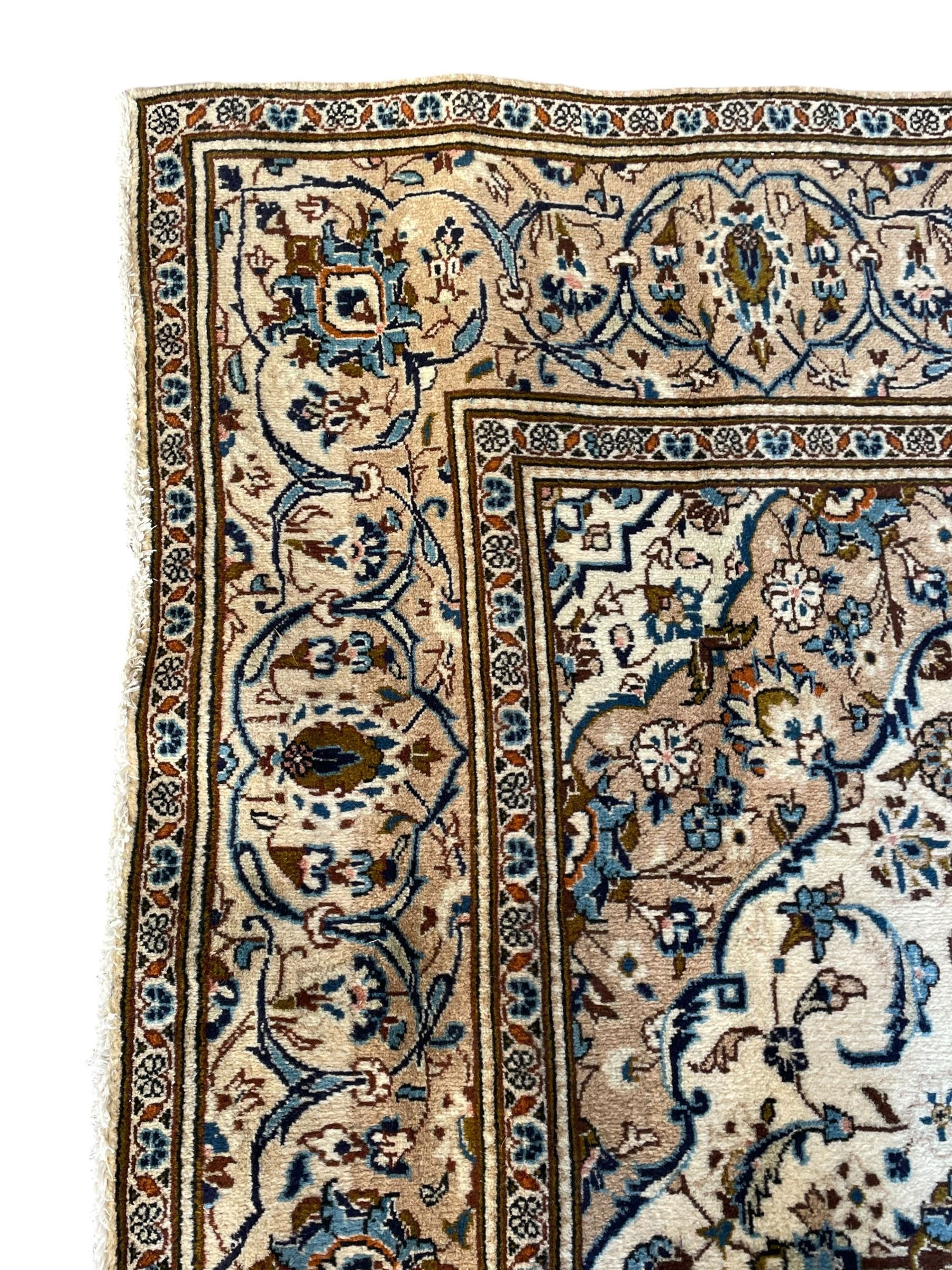 Persian Kashan ivory ground rug, the field decorated with interlacing branches and palmettes, central floral design pole medallion, the scrolling border decorated with stylised plant motifs, within repeating flower head guard stripes