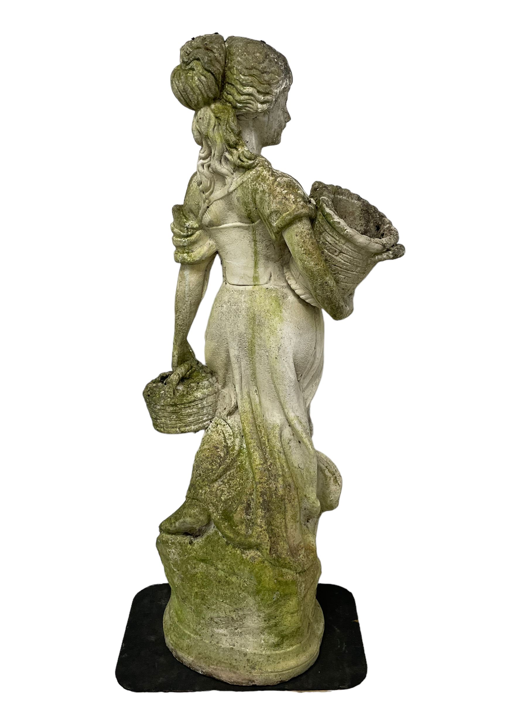 Weathered and painted cast stone garden statue, in the form of an Italian maiden carrying baskets with gathered flora and berries, on a shaped ovoid base