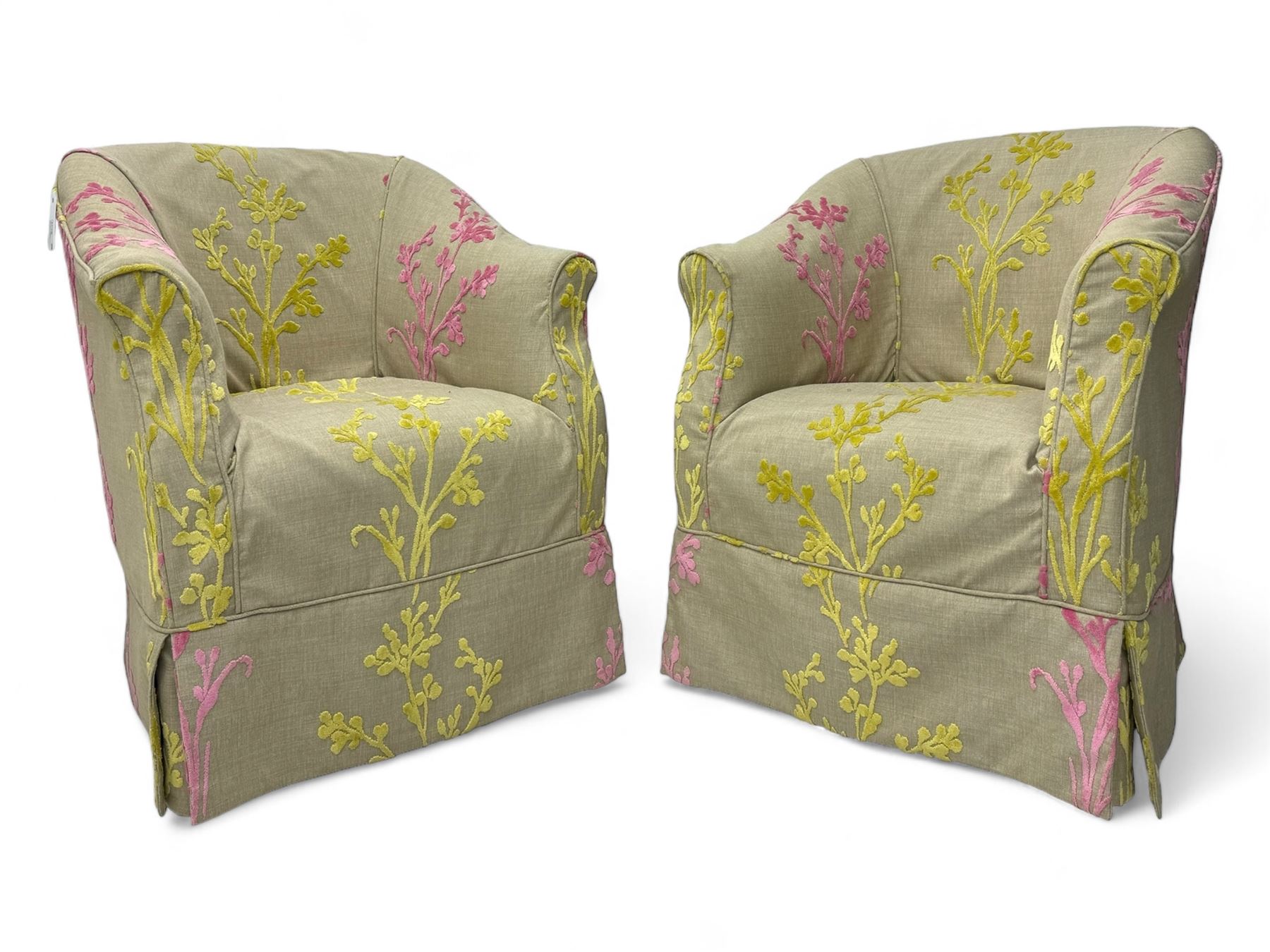 Pair of tub-shaped armchairs, mahogany frame loosely covered by branching floral pattern cover in pink and  yellow hues, skirted base, on concealed splayed rear and tapered front supports