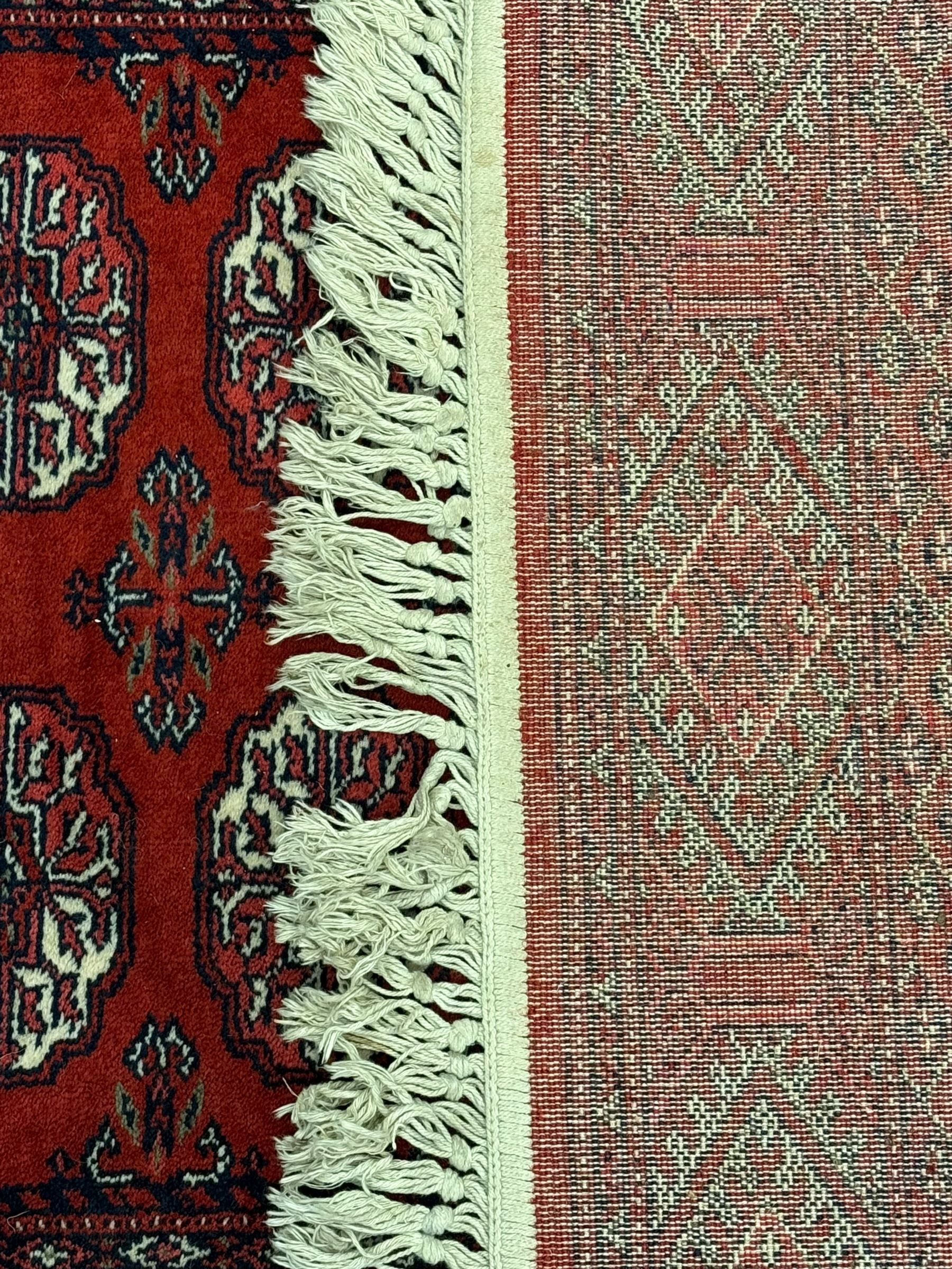 Persian Bokhara crimson ground runner rug, the field with a series of repeating ivory octagonal medallions, main border with repeating flower head pattern and diamonds within multiple guard stripes