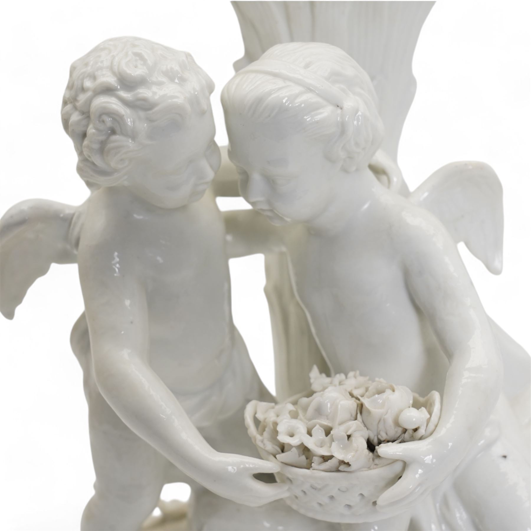 Pair of white porcelain candlesticks, originally candelabra, modelled as two cherubs holding a woven basket of flowers, perched before a tree trunk, possibly by Montreuil-sous-Bois, double crossed swords mark beneath and incised no. 1533, H23cm x W16.5cm 